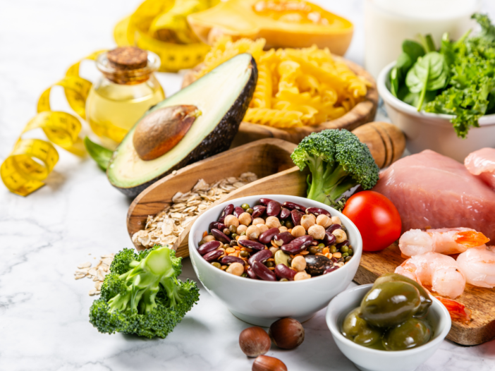 ingredients in a Mediterranean diet: avocado, beans, broccoli, olives, shrimp, pasta, olive oil