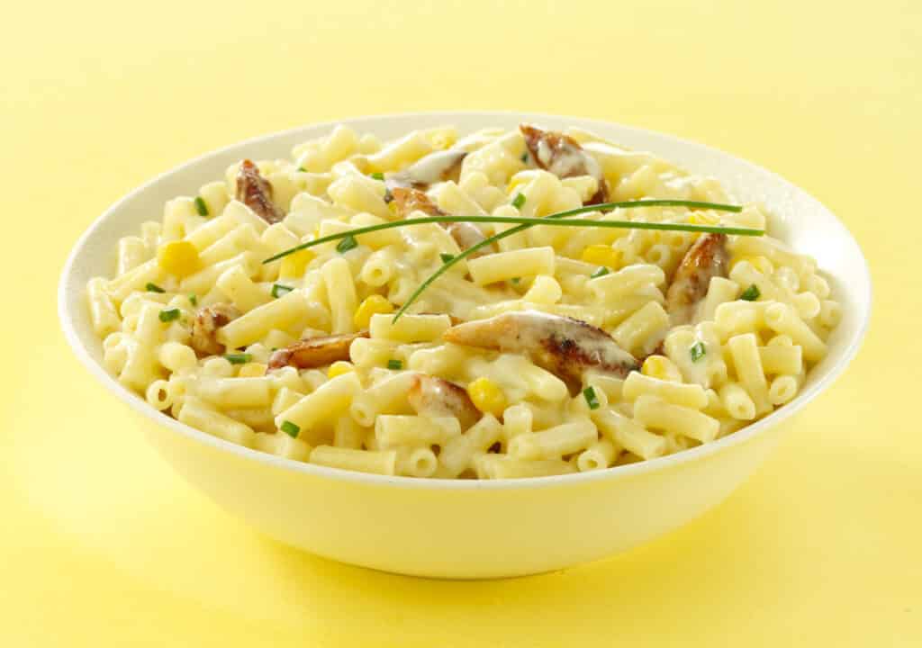 Bowl of Mac and Cheese with chicken, corn and chives added.