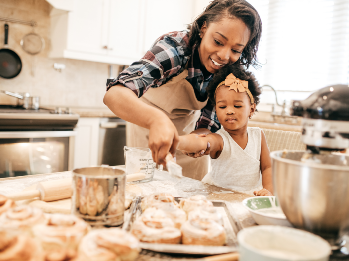 Mother and young daughter baking cinnamon rolls