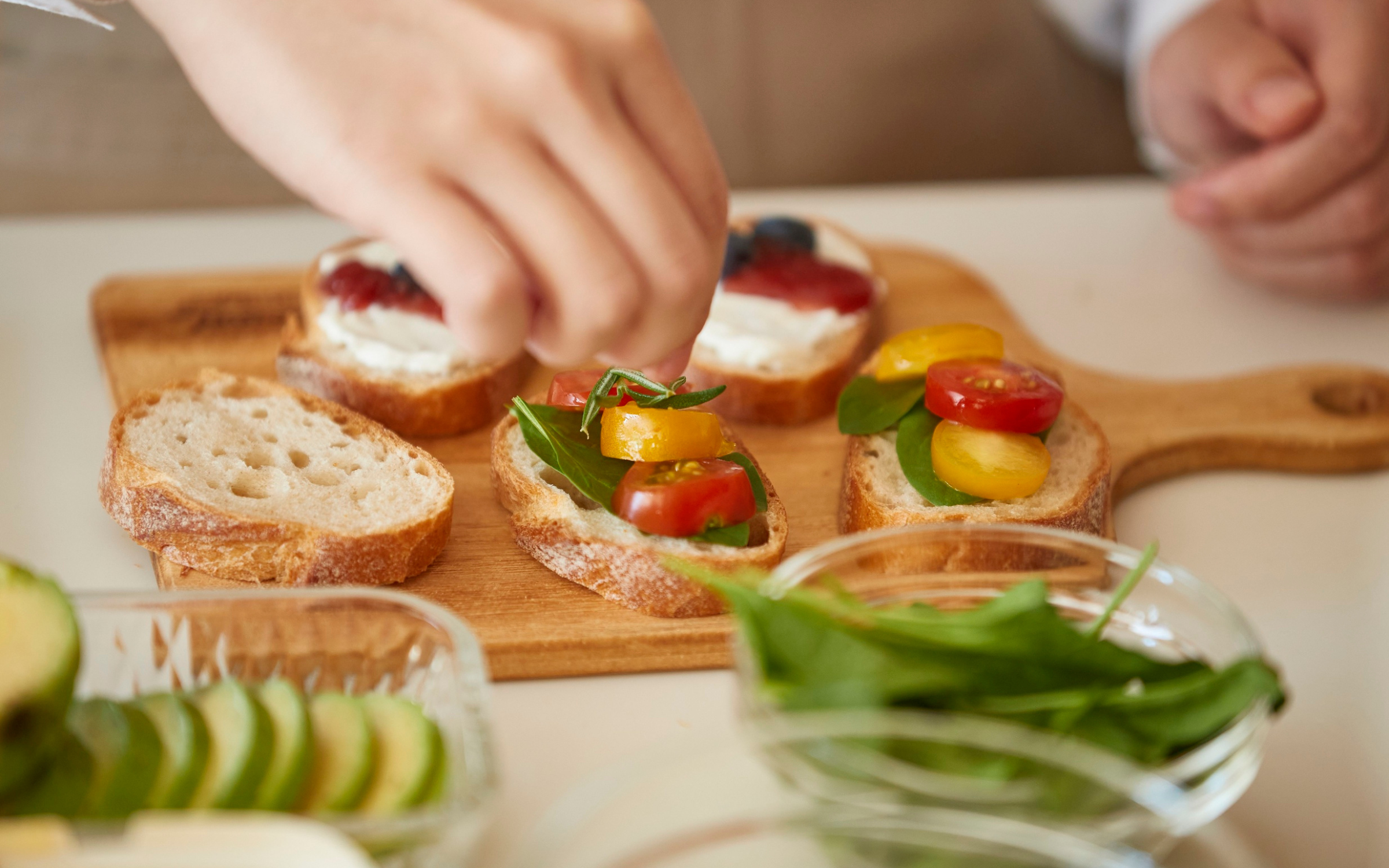 Woman topping crostini with herbs and tomatoes