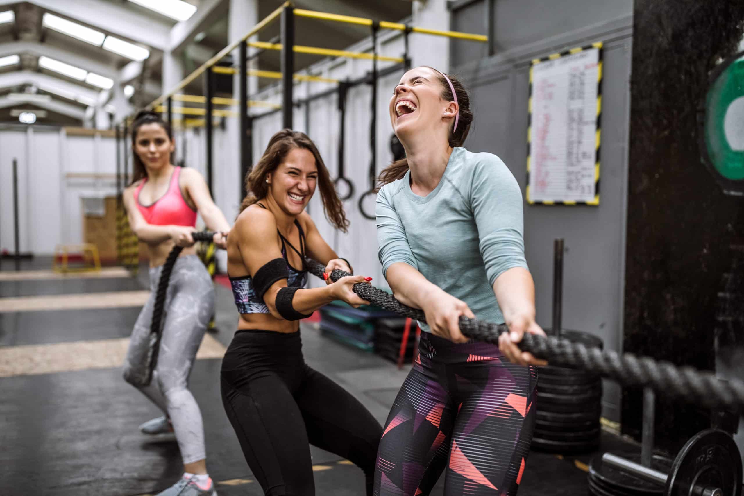 three women doing a battle rope workout in a gym